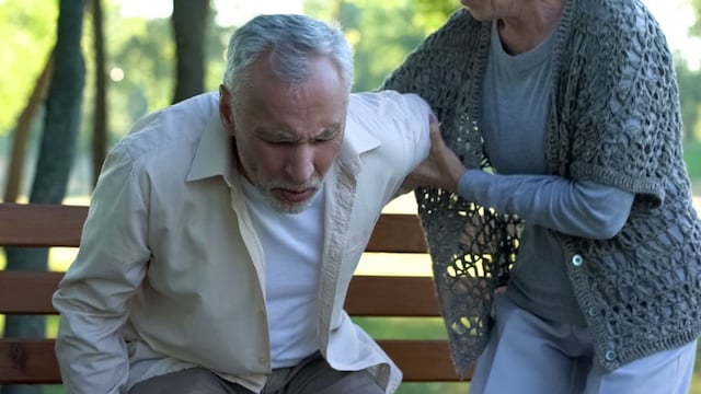 older woman helping man stand up from bench