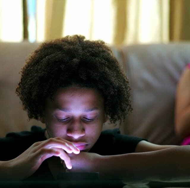 Teenager looking at a smartphone on a couch, illustrating concerns about social media addiction.